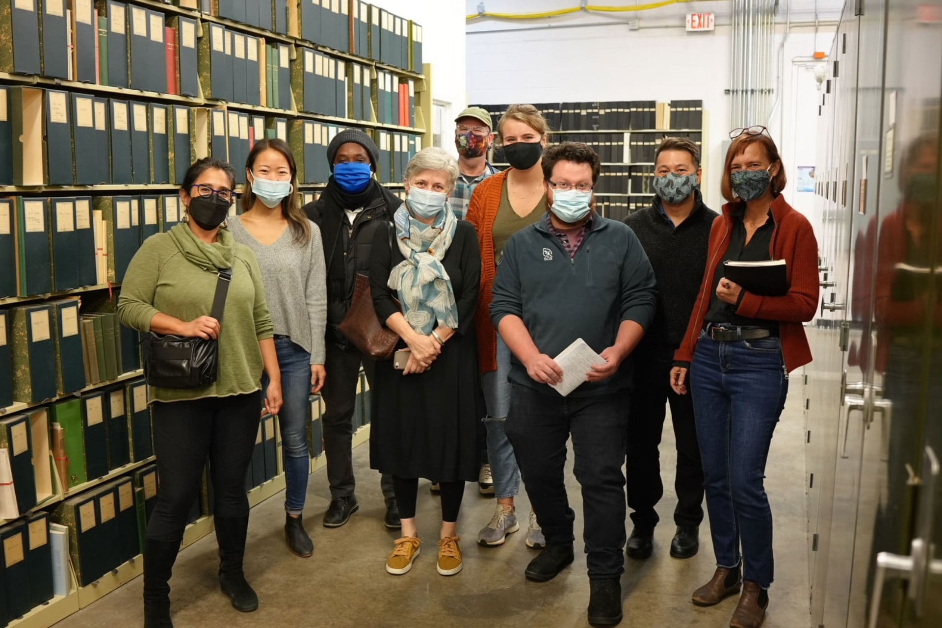 A group of people masked and standing among cabinets and shelves of file folders.