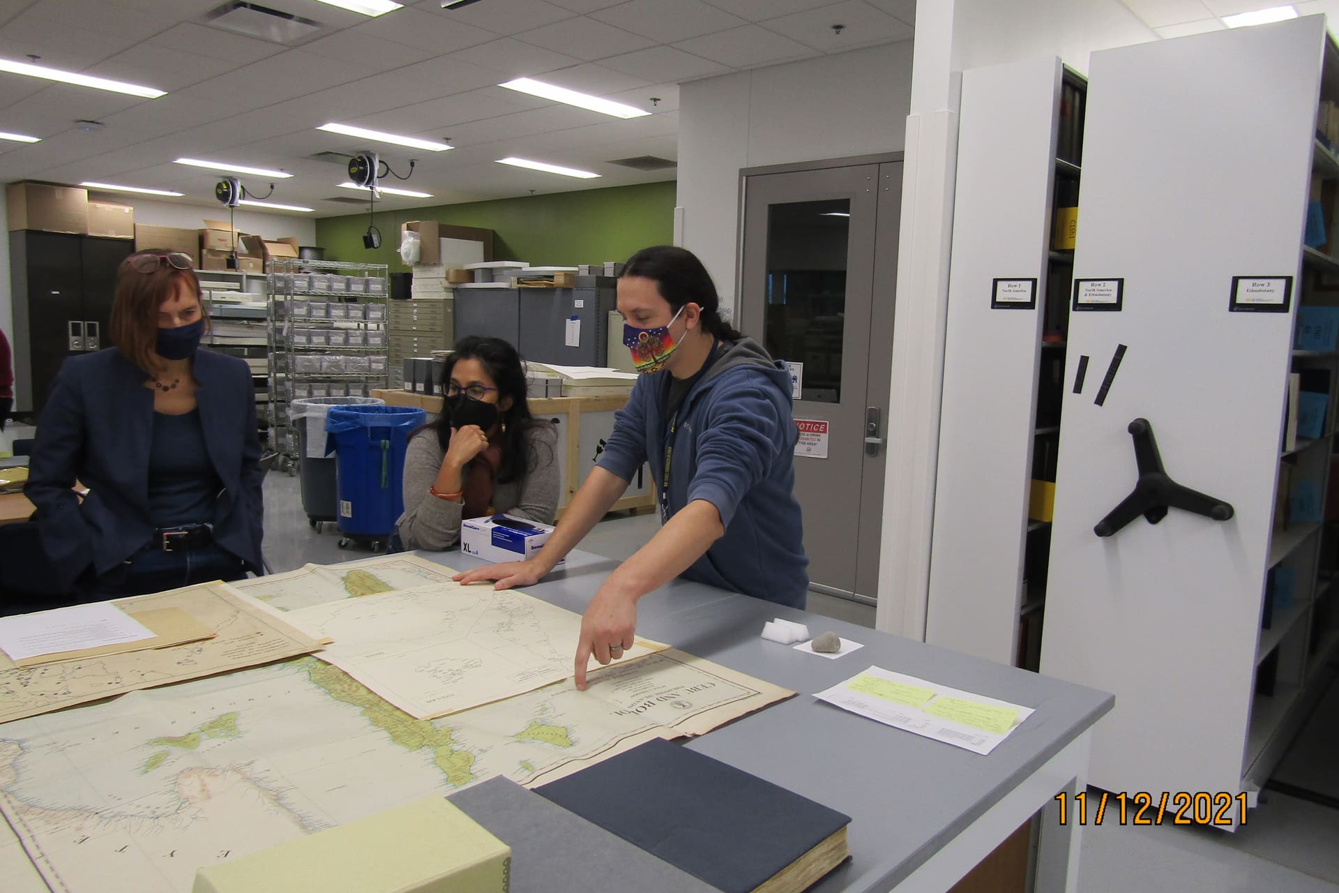 Three people looking at old maps.