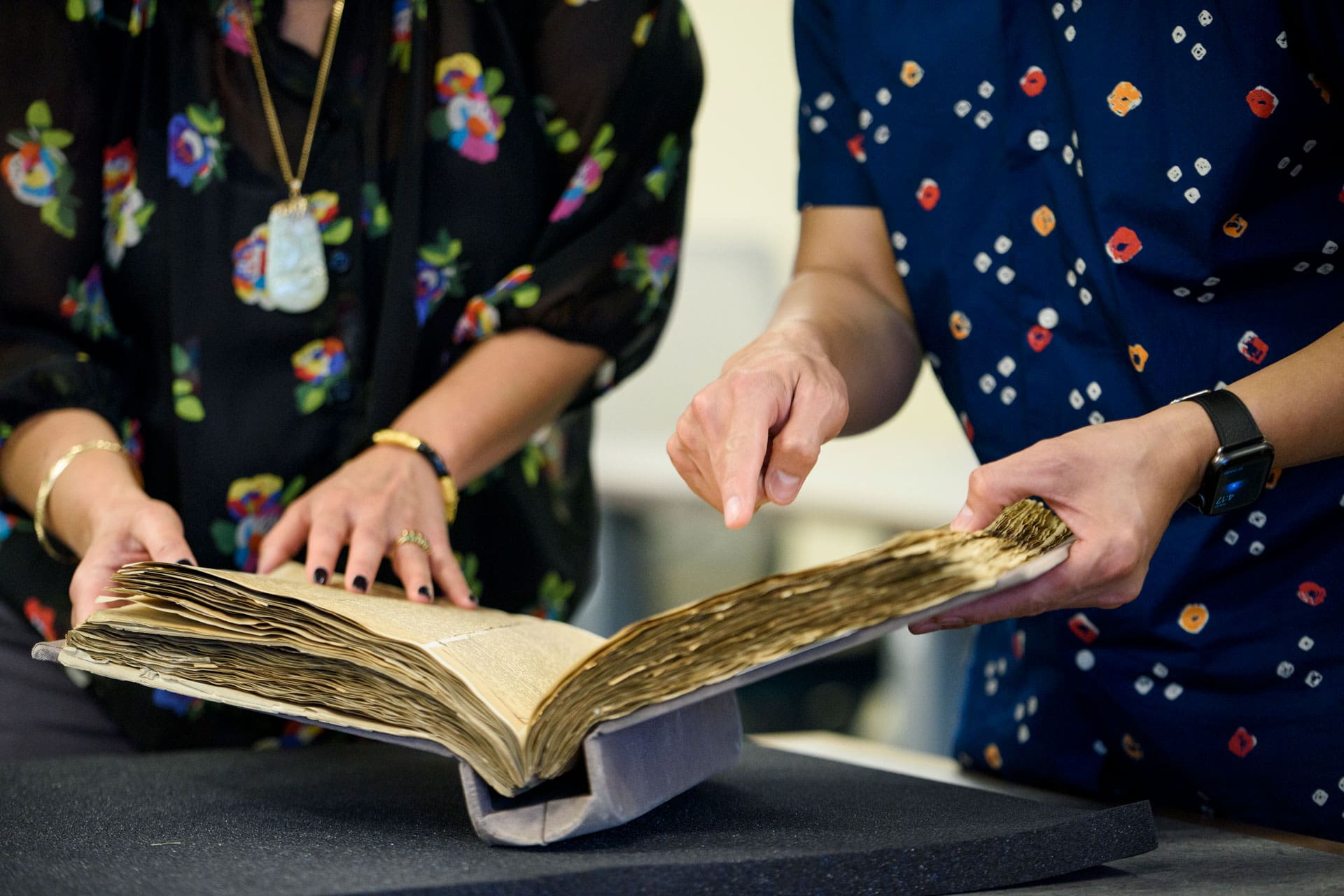 Two people looking closely at an archival manuscript.