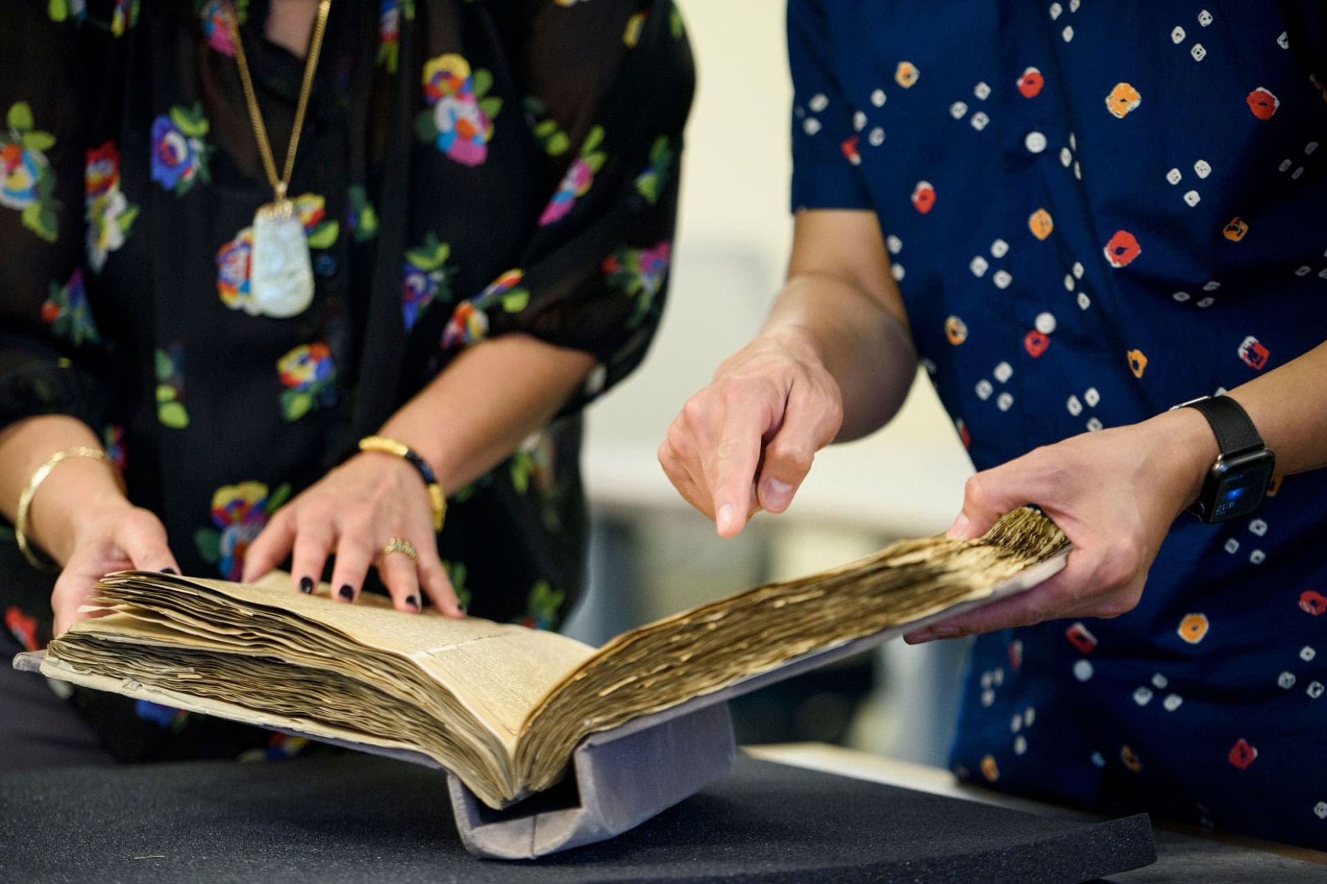 Close-up of two hands looking at an old manuscript.