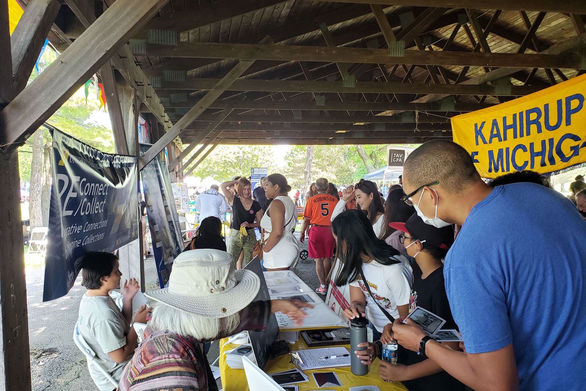 A crowd of people around an information table at a picnic.