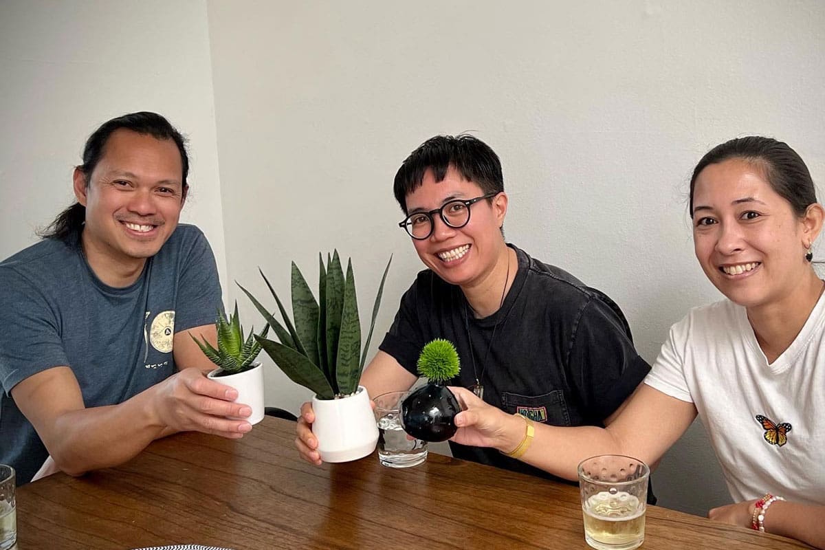 Three people seated holding plants