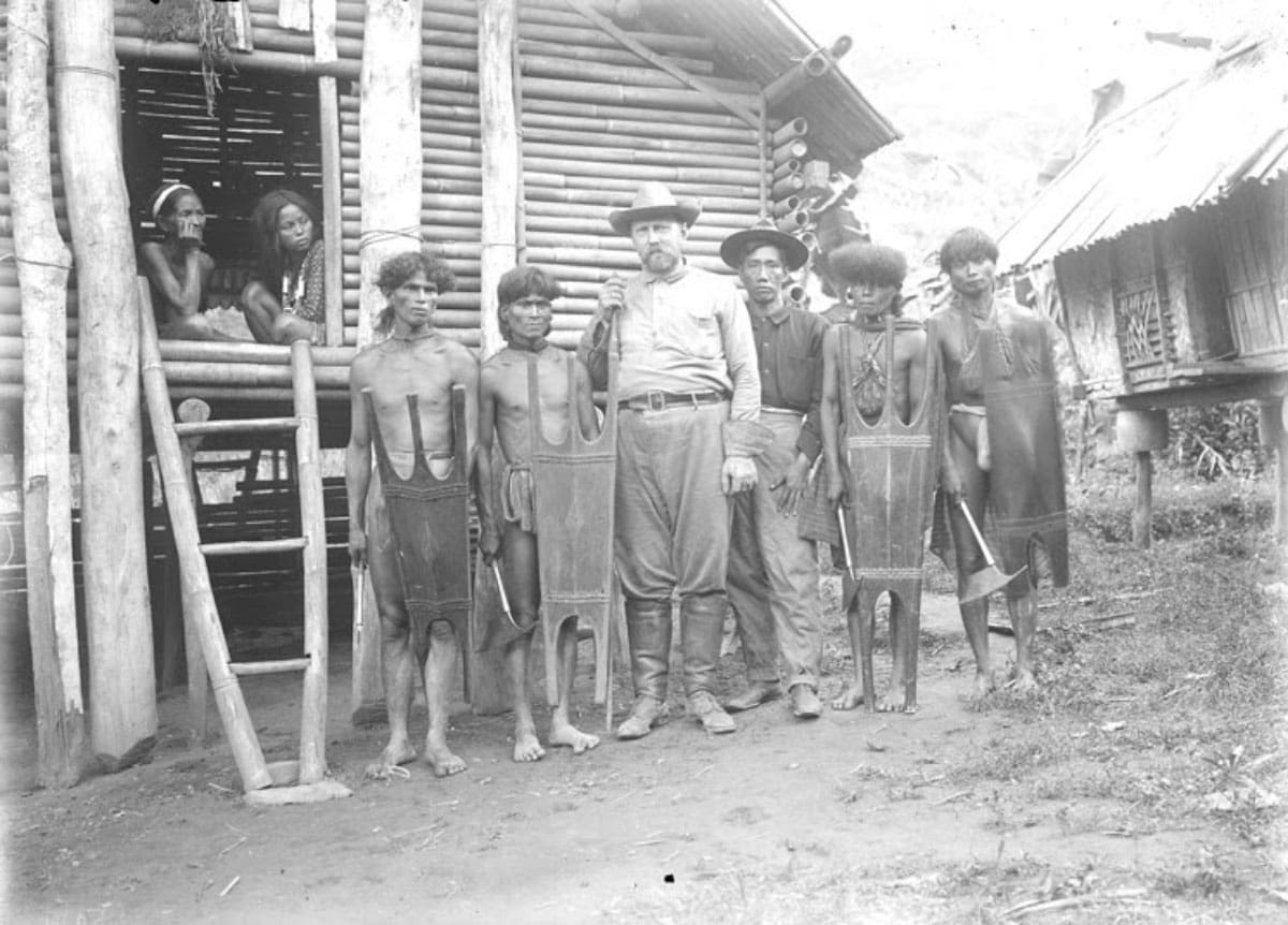 A colonialist standing with a group of indigenous people