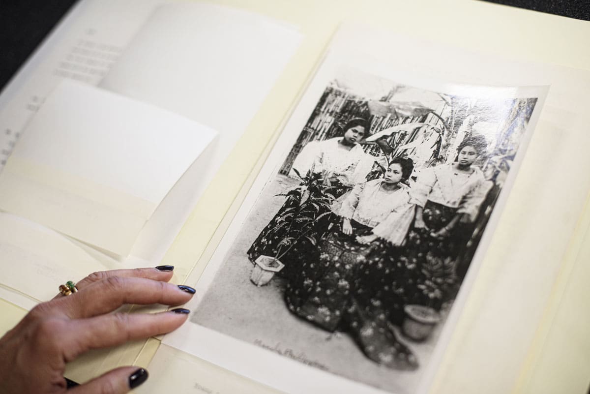 The hand of someone looking at an old photograph of three women