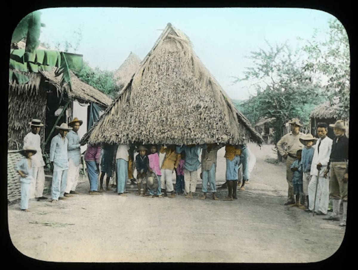 A group of people carrying and transporting a house.