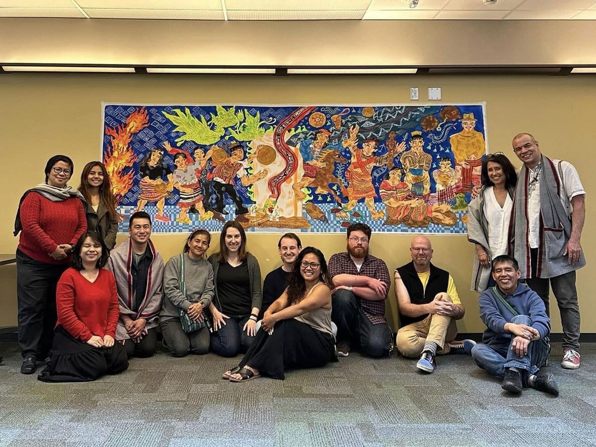 A group of people standing in front of a colorful mural.