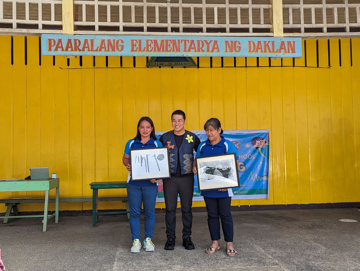 Three people holding framed photographs.