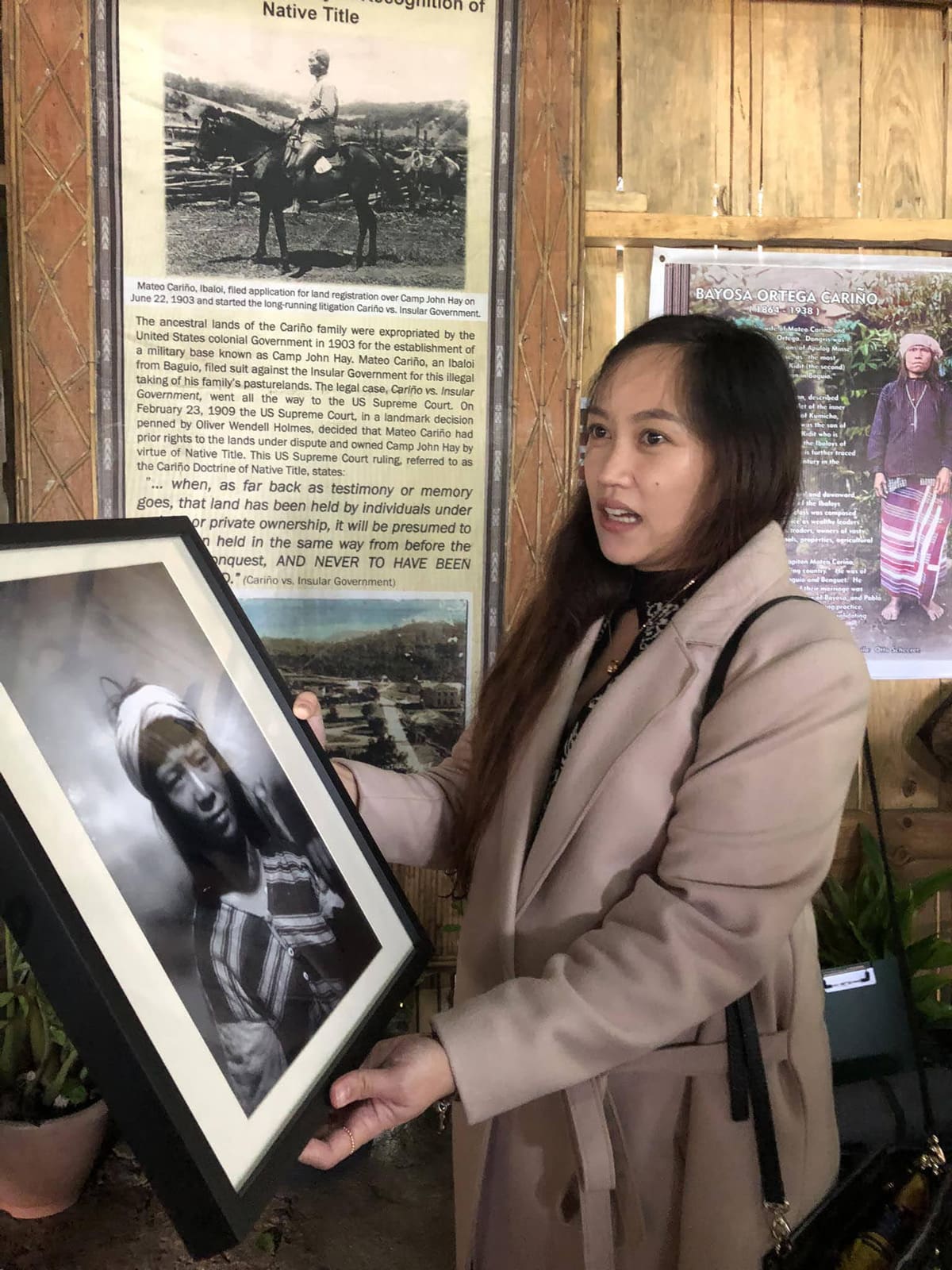 A woman holding a framed photograph from the past.