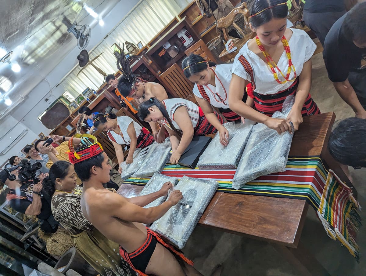 A group of people unwrapping framed photographs.