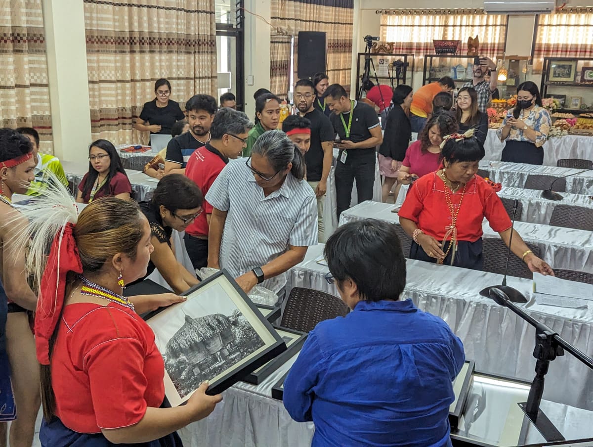 A crowd of people milling around old photographs