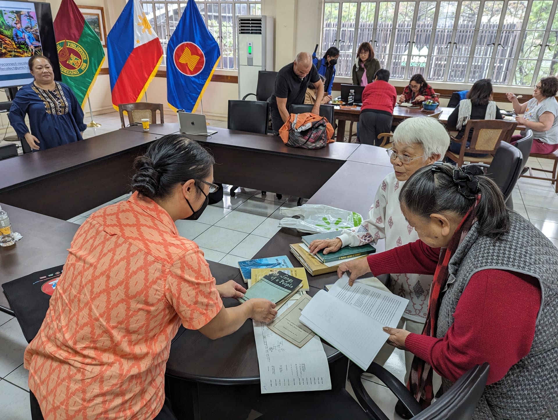 A group of people looking at books in a conference room