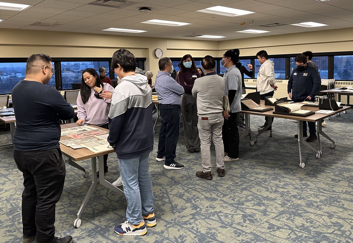 A small crowd of people looking at materials in a library