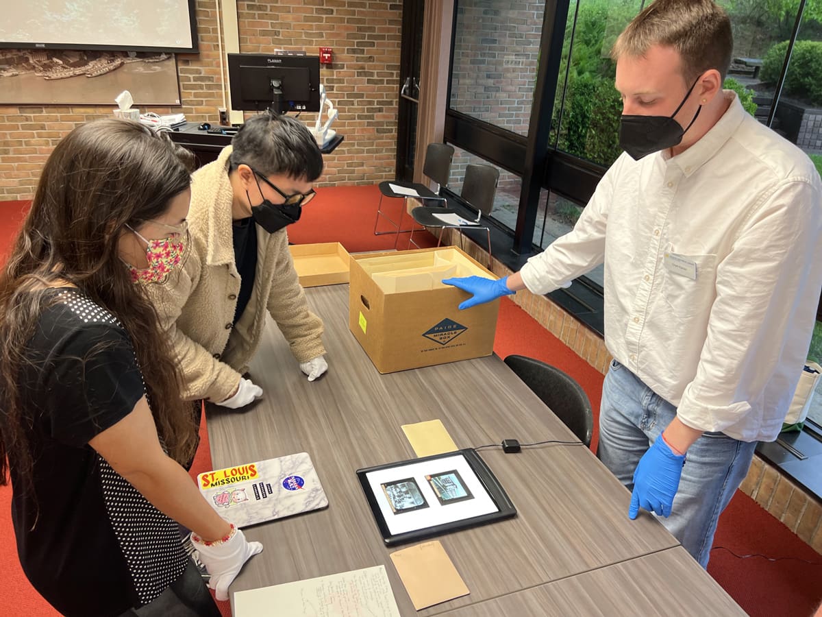 Three people examining lantern slides.