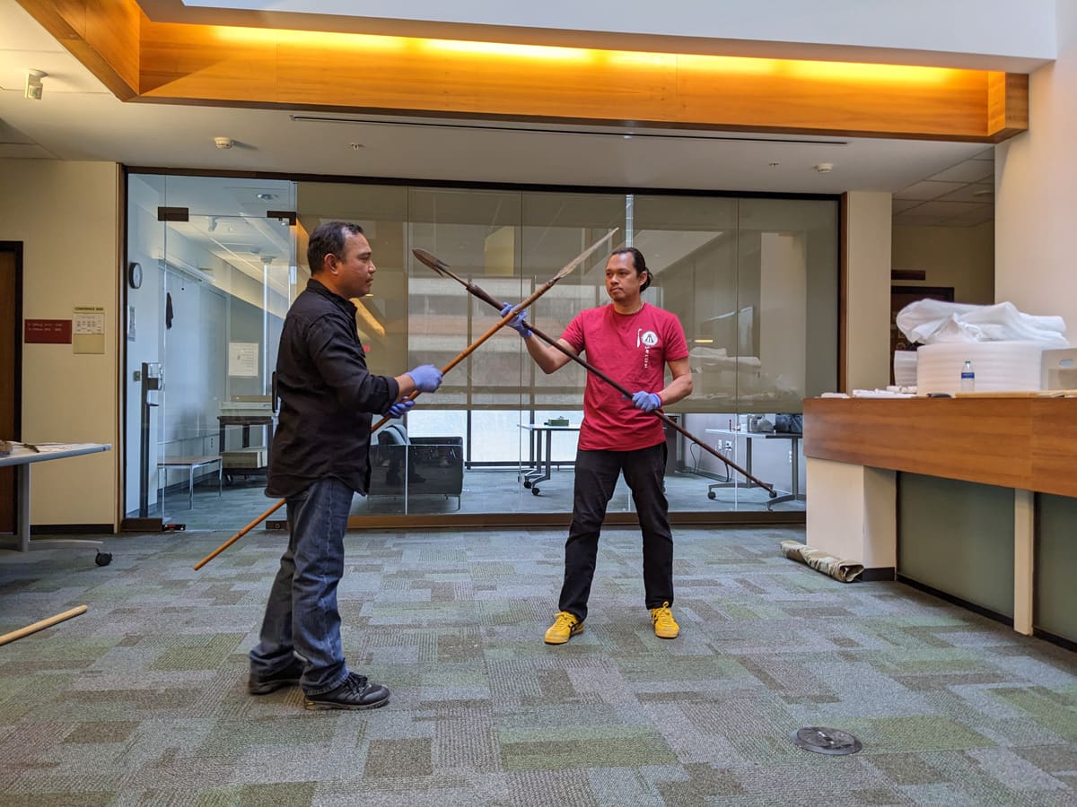 Two men demonstrating the use of spears.