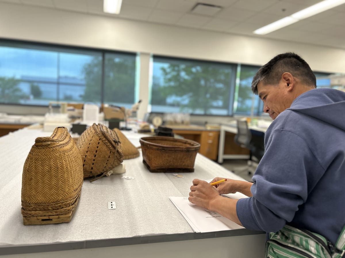 A man examines baskets from an archaeology collection.