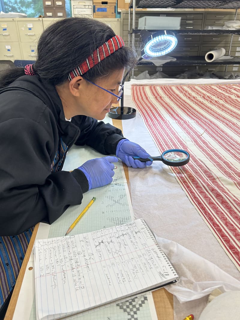 A woman examining a weaving pattern.